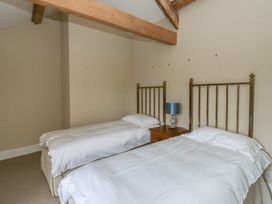 A bedroom with two beds and a lamp on a nightstand at North Cottage Llandovery