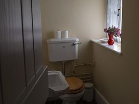 A bathroom with a toilet, tank, and a vase of flowers at North Cottage Myddfai near Llandovery