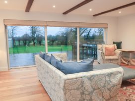 A living room with a sofa and armchair overlooking a garden at Peewit Coach House in Moreton-in-Marsh