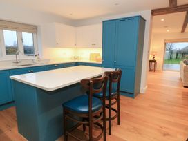 A kitchen with a blue island and bar stools at Peewit Coach House in Moreton-in-Marsh
