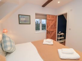A bedroom with a bed and window at Peewit Coach House in Moreton-in-Marsh