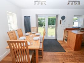 A dining room with a wooden table and chairs at Hawthorns in Swansea