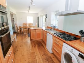 A kitchen with wood cabinets and a dining area at Hawthorns in Swansea