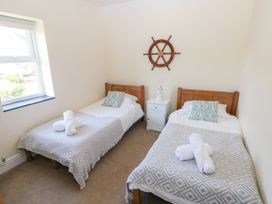 A bedroom with two beds and a bedside table at Hawthorns in Swansea