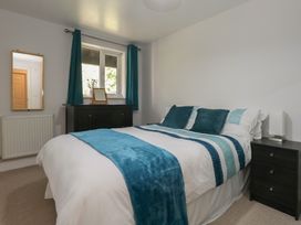 A bedroom with a bed and a mirror at June Cottage in Wool