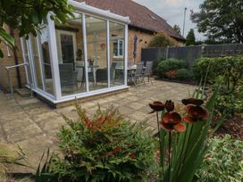 A garden with a glass conservatory and patio seating at June Cottage in Wool