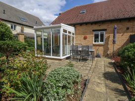 A garden with a conservatory and outdoor seating at June Cottage in Wool
