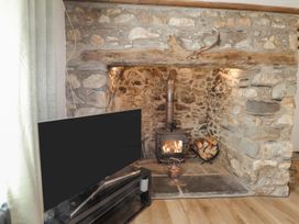 A living room with a wood stove and television at Clawddcam in Mathry