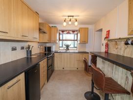 A kitchen with wood cabinets and bar stools at Clawddcam in Mathry