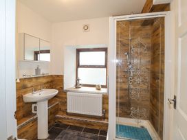 A bathroom with a sink, mirror, shower, and radiator at Clawddcam in Mathry