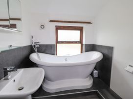 A bathroom featuring a bathtub, sink, and window at Clawddcam in Mathry