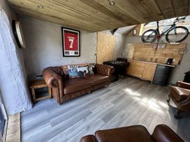 A snug with a leather sofa and kitchen area at Clawddcam in Mathry