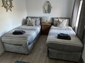 A bedroom with two beds and a nightstand at Clawddcam in Mathry