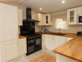 A kitchen with cabinets, oven, sink, and countertop at The Chalet at Tyn Lon Chwilog