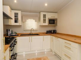 A kitchen with a sink and kitchen appliances at The Chalet at Tyn Lon in Chwilog
