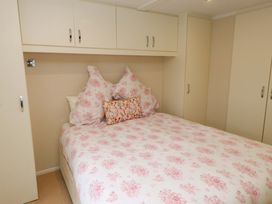 A bedroom with a bed and storage cabinets at The Chalet at Tyn Lon in Chwilog