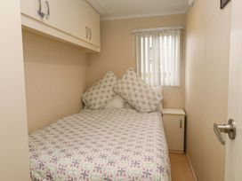 A bedroom with a bed and bedside cabinet at The Chalet at Tyn Lon, Chwilog