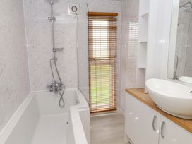 A bathroom with a bathtub, sink, and window at The Chalet at Tyn Lon in Chwilog