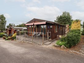 A wooden cabin with a deck and outdoor furniture at Charnwood