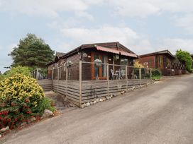 A wooden cabin with a fence and outdoor furniture at Charnwood 