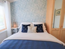 A bedroom with a bed, cushions, nightstand and wardrobe at Charnwood