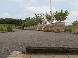 A gravel area with a stone wall and trees at Two Parks Barn Upton Bishop near Ross-On-Wye
