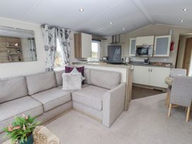 A living room with a sofa and kitchenette at Bryncrin Edern