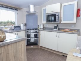 A kitchen with a stove, microwave, sink and cabinets at Bryncrin in Edern