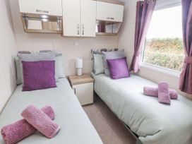 A bedroom with two beds and a side table at Bryncrin in Edern
