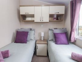 A bedroom with two single beds and storage at Bryncrin in Edern