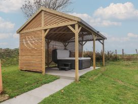 An outdoor area with a hot tub under a wooden structure at Bryncrin Edern near Morfa Nefyn