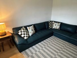A living room with a sectional sofa and lamp at Knocknanuss