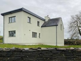 A house with a stone wall and grass area at Knocknanuss in 