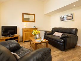 A living room with a sofa and television at 2 Riverside Cottages in Ambleside