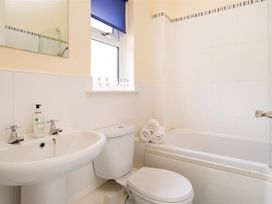 A bathroom with a wash basin, toilet, and bath at 2 Riverside Cottages in Ambleside