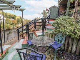 A patio with table and chairs by a river at Bryn Dwr in Llangollen