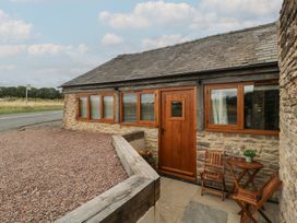 An outdoor area with a table and chairs in front of a stone building at The Old Cart Shed in Gorsley