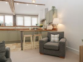 A kitchen with a counter and stools at The Old Cart Shed in Gorsley