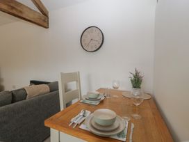 A dining area with a table set with dishes and a clock at The Old Cart Shed in Gorsley