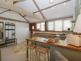 A kitchen with a table and stools at The Old Cart Shed in Gorsley