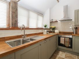 A kitchen with a sink, cabinets, oven, and window at The Old Cart Shed, Gorsley
