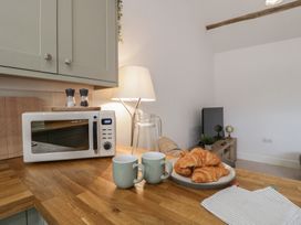 A kitchen with a microwave, cups, and croissants at The Old Cart Shed in Gorsley