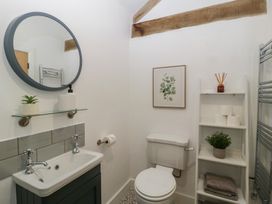 A bathroom with sink, toilet, and decorative shelf at The Old Cart Shed in Gorsley