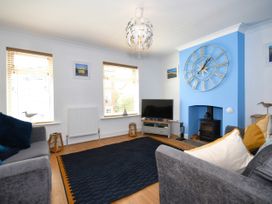 A living room with a TV and a clock at Seahorse in Filey