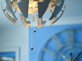 A chandelier with pull chains and a clock in the background at Seahorse in Filey