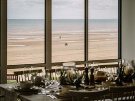 A dining room with a view of the beach and people walking at Calm Waters Luxury Beach House in Bridlington