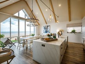 A kitchen with a dining area and large windows at Calm Waters Luxury Beach House, Bridlington