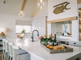 A kitchen with an island featuring flowers and food at Calm Waters Luxury Beach House in Bridlington