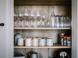 A kitchen cupboard with glassware and mugs at Calm Waters Luxury Beach House in Bridlington