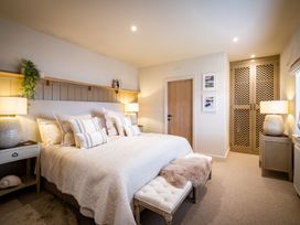 A bedroom with a bed, bedside table and wardrobe at Calm Waters Luxury Beach House in Bridlington